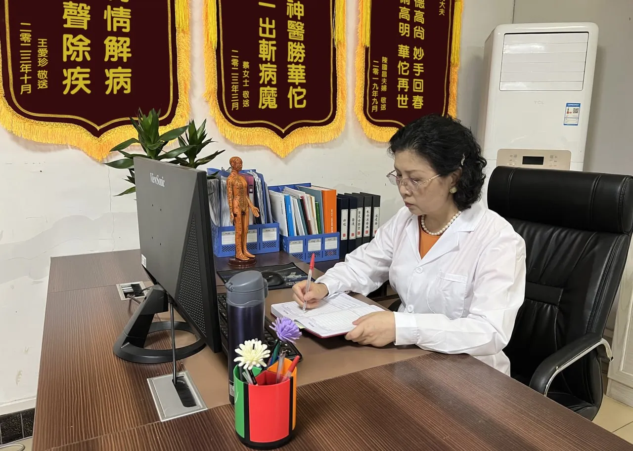 患者致贈錦旗懸掛於診室，醫師於桌前問診